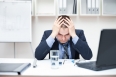 Depressed young business man holding his head at office