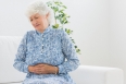 Elderly woman having a belly pain in the living room