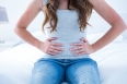 Brunette suffering from stomach pain at home in the bedroom