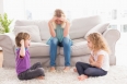 Upset woman sitting on sofa while brother teasing sister at home