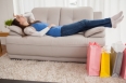 Woman lying on couch with shopping bags at home in the living room