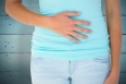 Slim woman with hand on stomach against painted blue wooden planks