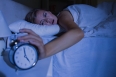 Awakening woman stopping her alarm clock at night in the bedroom