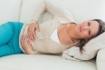 Woman lying on the sofa in the living room with upset stomach