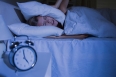 Blond woman putting pillows on her ears at night