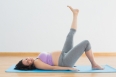 Pregnant woman lying on mat lifting her leg in a fitness studio