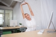 Young businesswoman stretching hands in office