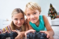 Happy siblings playing video games on floor at christmas time