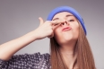 Young woman holding up fingers on nose and making silly expression