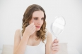 Woman plucking her eyebrows while looking into a mirror